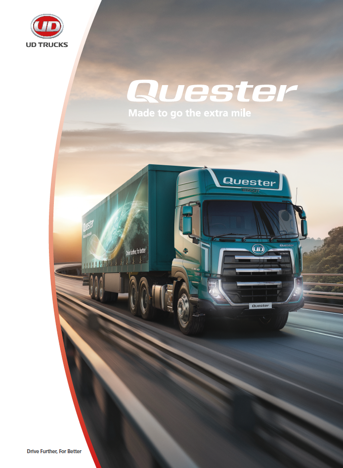 Green Quester truck driving on a highway at sunrise.