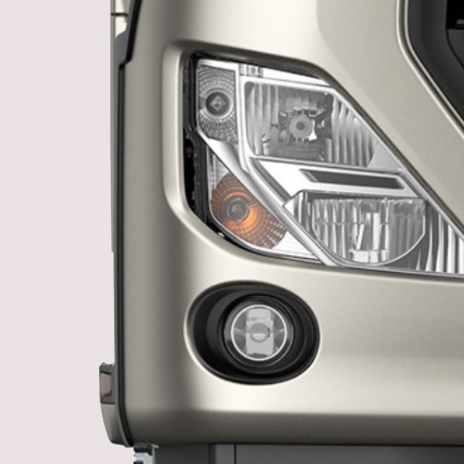Close-up of a silver truck's headlight and fog light.