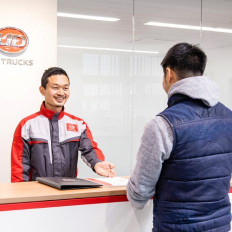 Man in uniform smiling and helping customer at a modern reception desk.