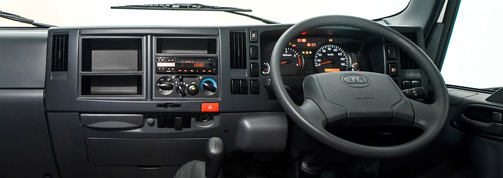 Truck dashboard with steering wheel, gear shift, and front windshield visible.