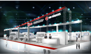 屋内展示会で大型トラック数台が照明の下に並ぶブース