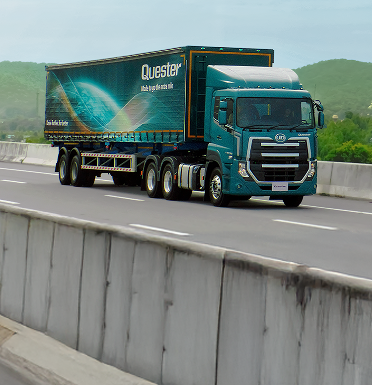 Blue semi-truck with a trailer driving on a highway, hills in the background.